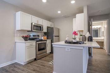 a kitchen with white cabinets and stainless steel appliances at Saw Mill Village apartments